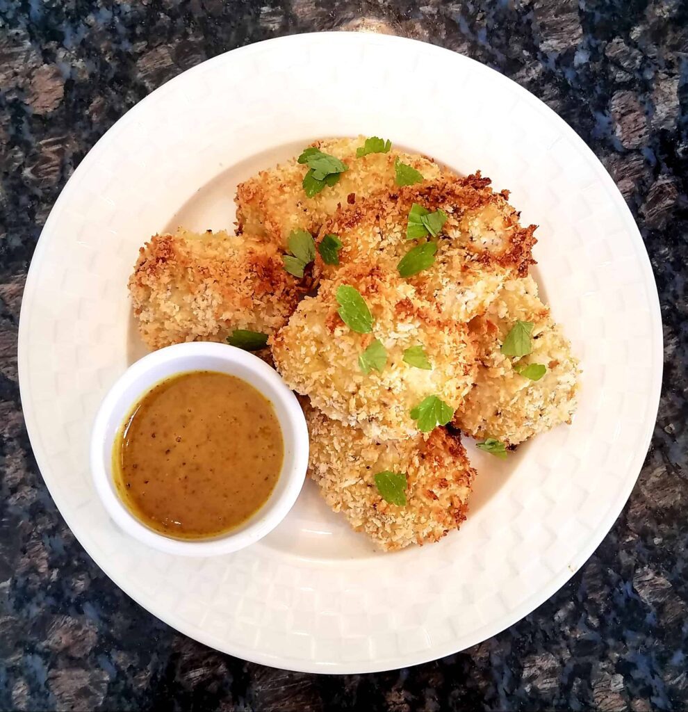 A plate of crispy chicken tenders with a side of honey mustard dipping sauce.