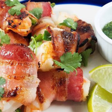 A close up of bacon wrapped jalapeno stuffed shrimp.