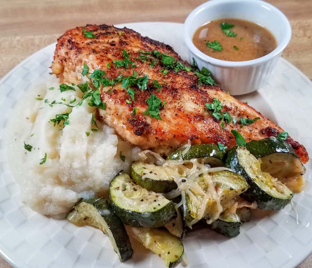 A plate of oven roasted chicken breasts with zucchini and mashed cauliflower.