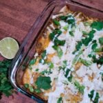 A casserole dish filled with chicken enchiladas with roasted tomatillo sauce.