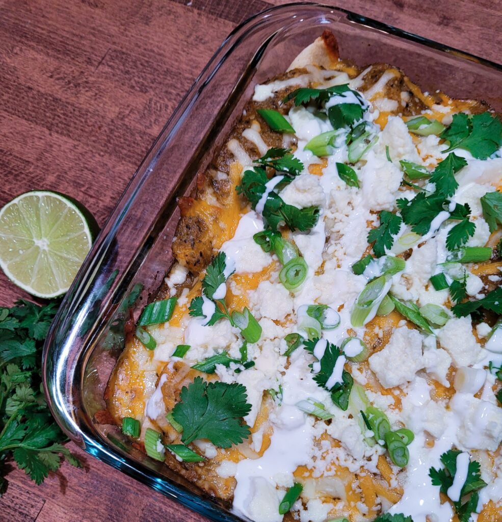 A casserole dish filled with chicken enchiladas with roasted tomatillo sauce.