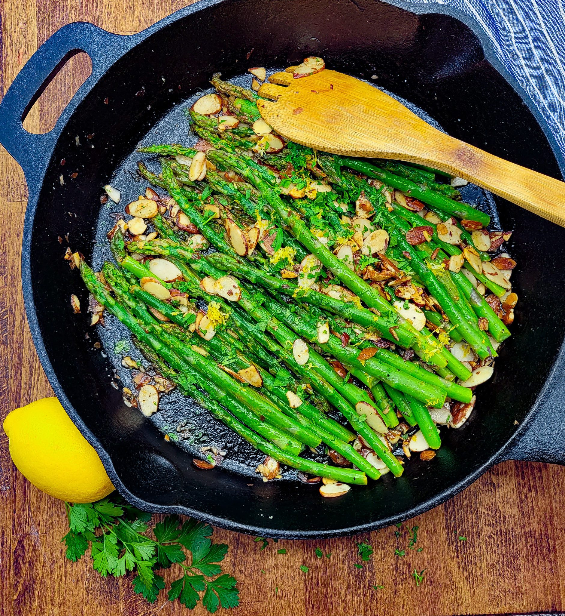 A skillet with vibrant green asparagus amandine with lemon and parsley.