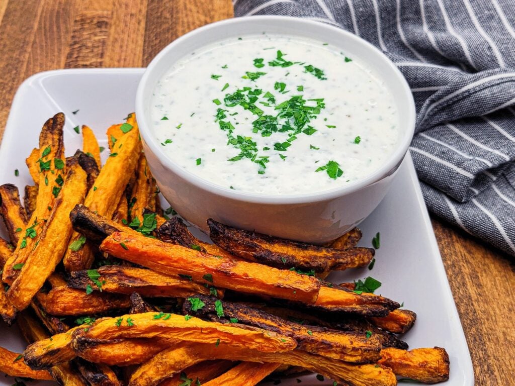 A plate of air fryer carrots and an herbed Greek yogurt dipping sauce.