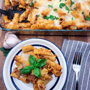 A plate of pasta al forno and a casserole dish with pasta al forno, hot out of the oven.
