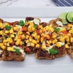 A rectangular platter of blackened mahi mahi filets with sliced lime and habanero mango salsa
