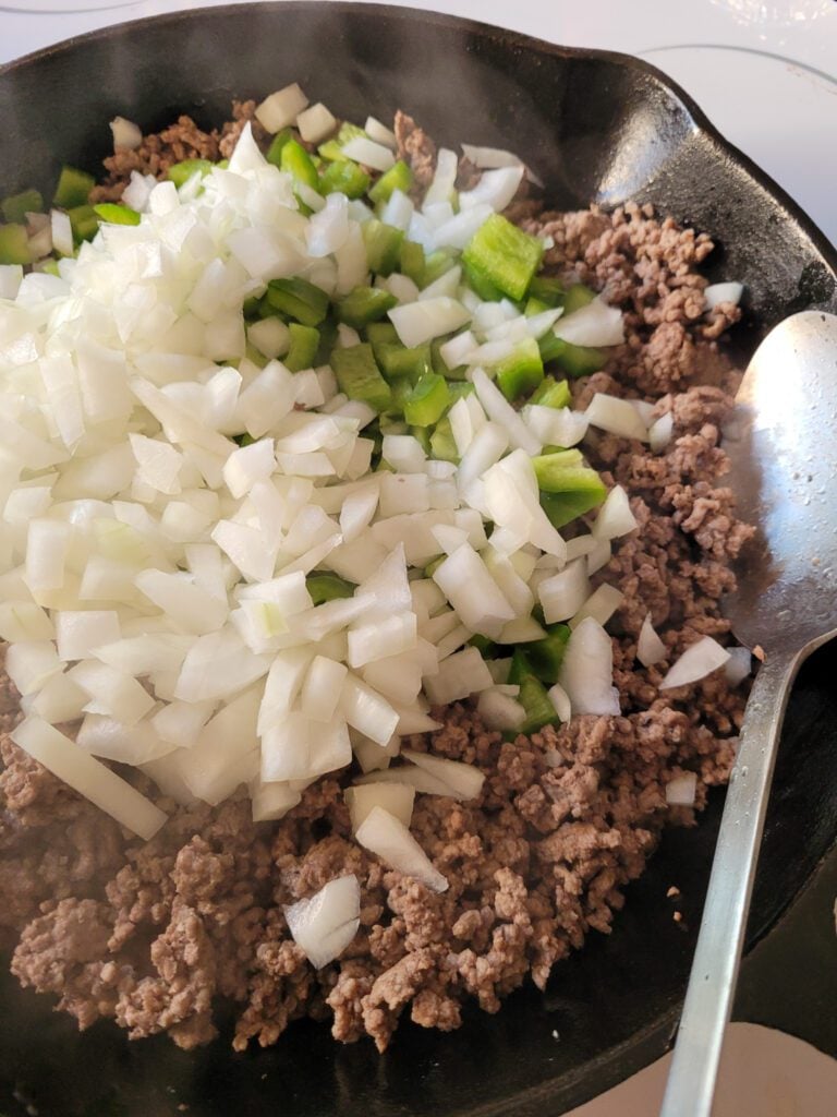A skillet of browned ground beef with onions and green bell peppers