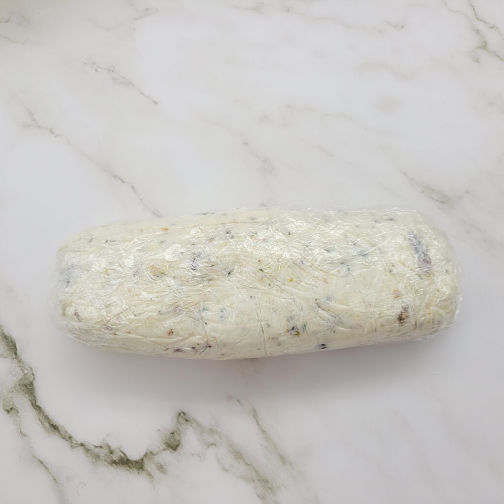 A plastic wrapped Cranberry Pistachio Cheese Log
