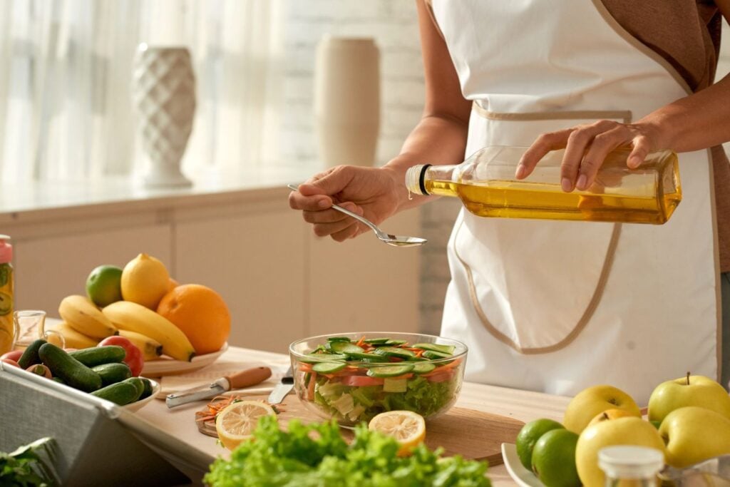 A woman in a white apron measuring olive oil