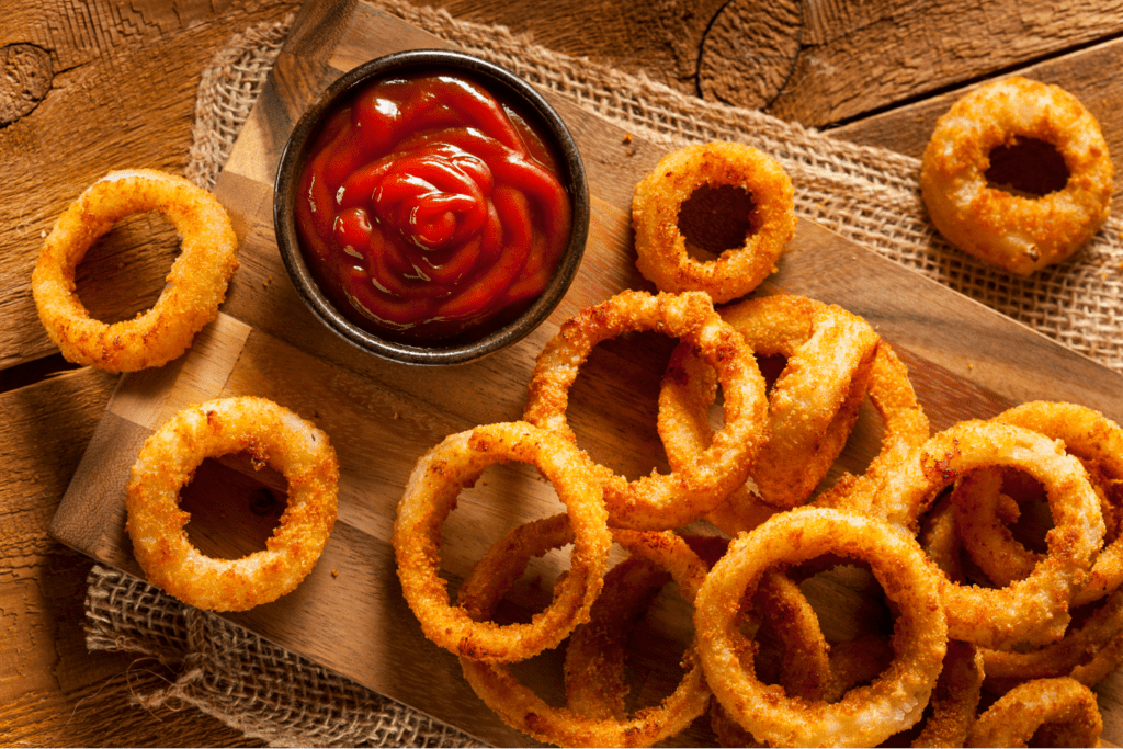 A pile of onion rings with ketchup on the side