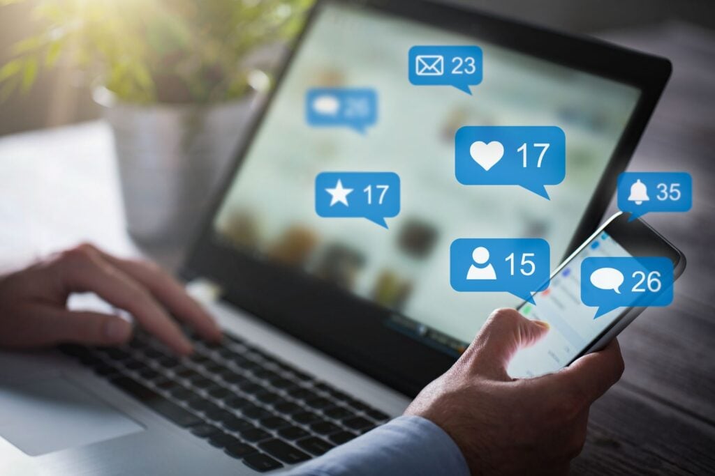 A laptop with social media icons floating out of it
