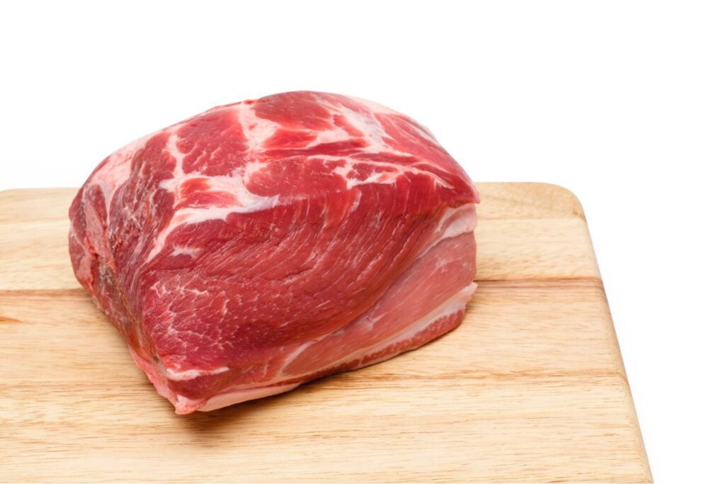 A raw pork shoulder on a cutting board
