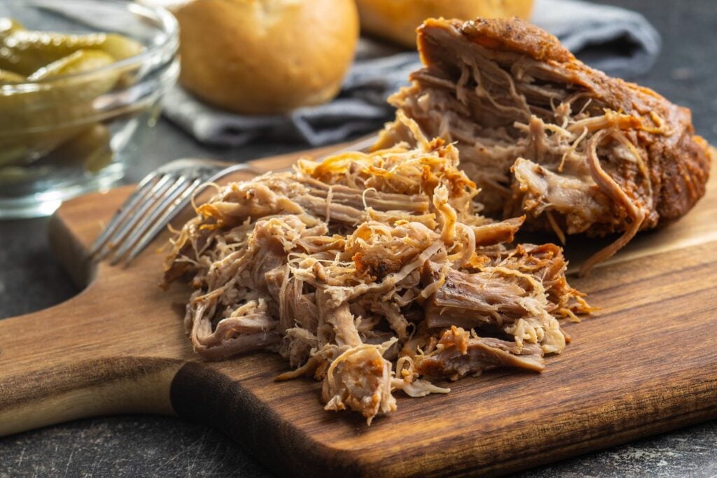 A cutting board with tender, juicy pulled pork