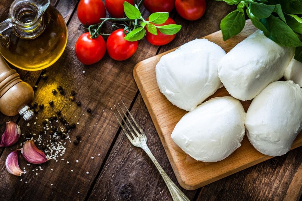A layout of burrata cheese balls. vine cherry tomatoes, and various herbs and spices